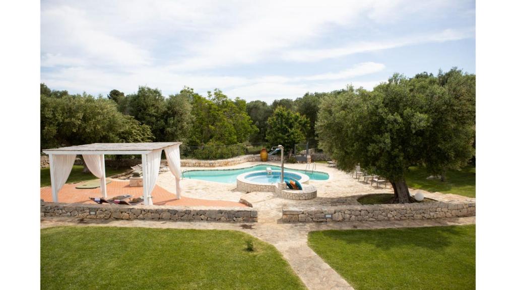 une image d'une piscine avec un kiosque dans l'établissement trullo degli ulivi con piscina e vasca per bambini, à San Michele Salentino