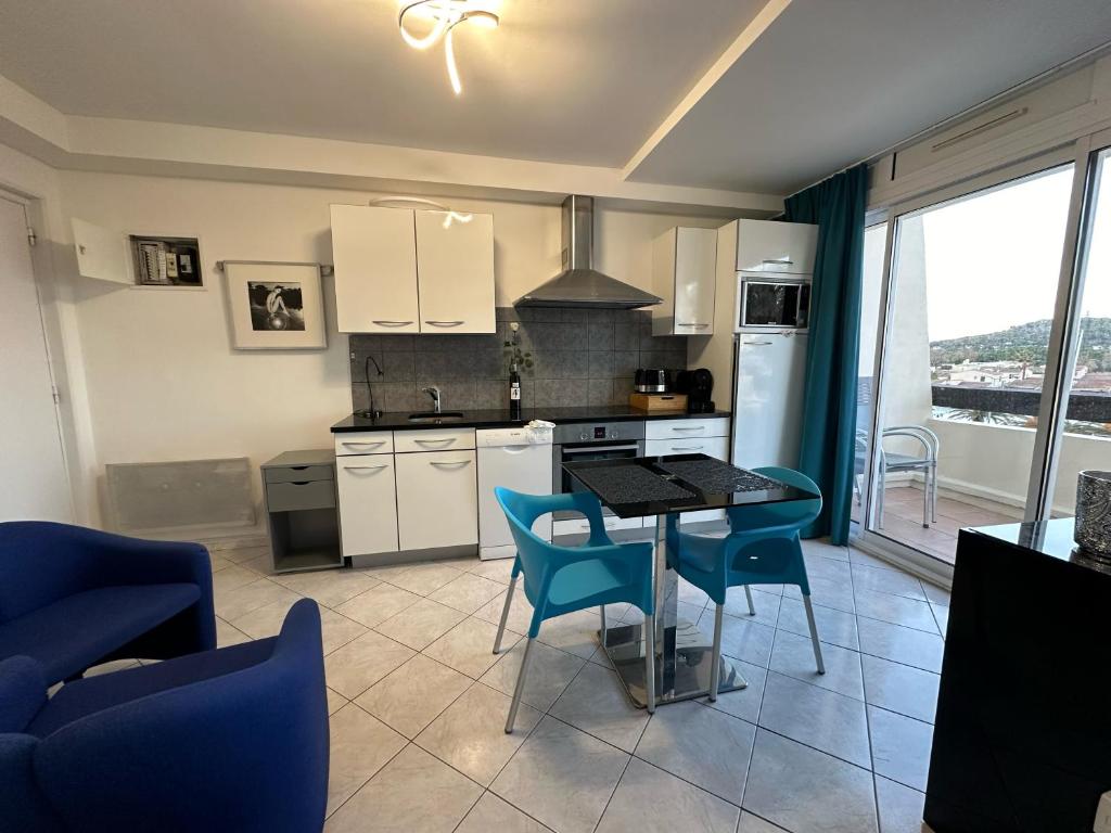 - une cuisine avec une table et des chaises bleues dans la chambre dans l'établissement Village naturiste - Port-Nature 7 - Le Maryline - 3ème étage - vue Port, au Cap d'Agde