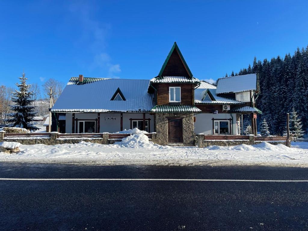 a house on the side of the road with snow at Guest House Zator in Vyshkiv