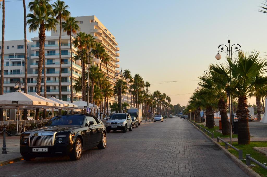 a black car parked on a street with palm trees at The Josephine Boutique Hotel in Larnaka