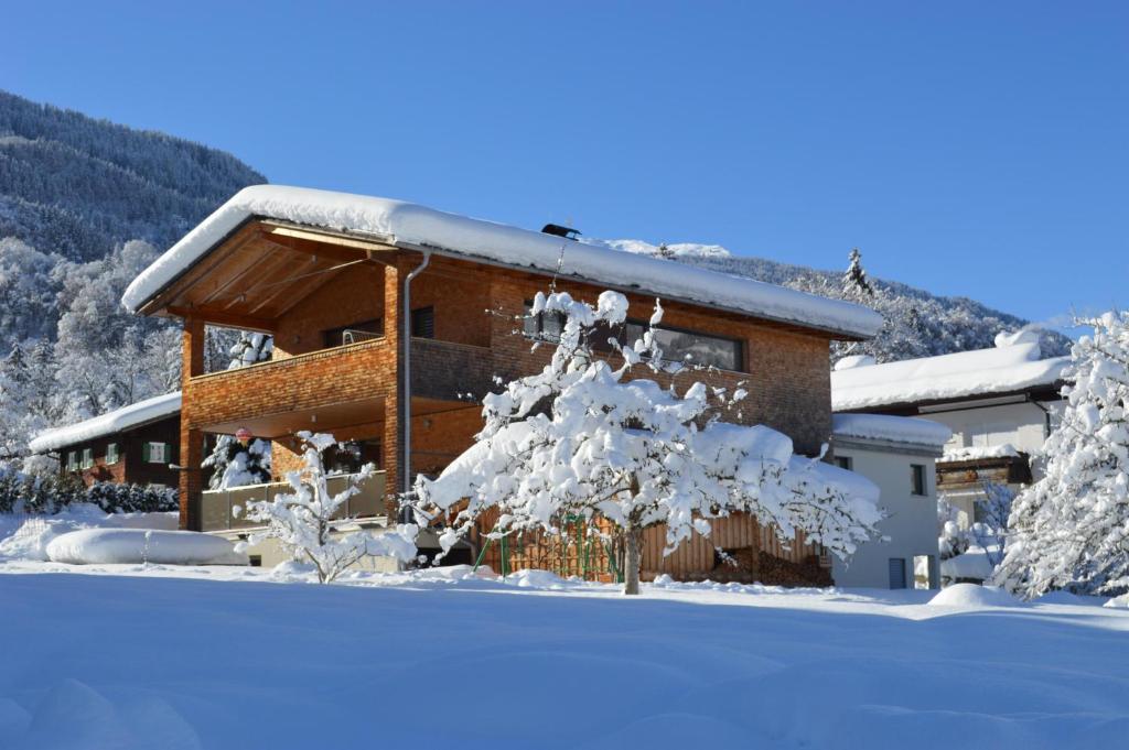 a log cabin in the snow with a snow covered tree at Chalet Keßler in Tschagguns