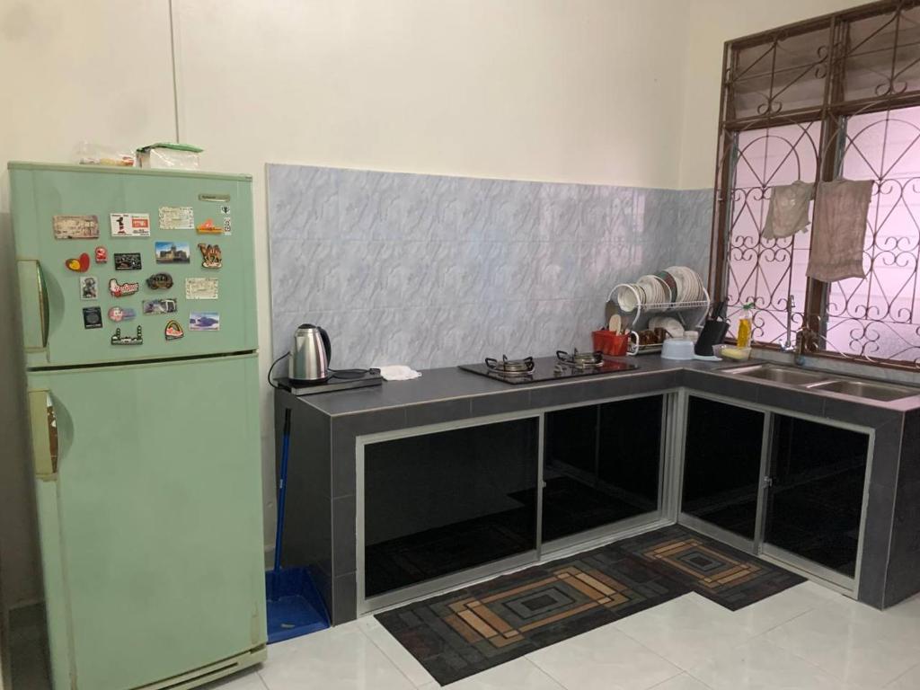 a kitchen with a counter and a refrigerator at Zahra Homestay in Rantau Panjang