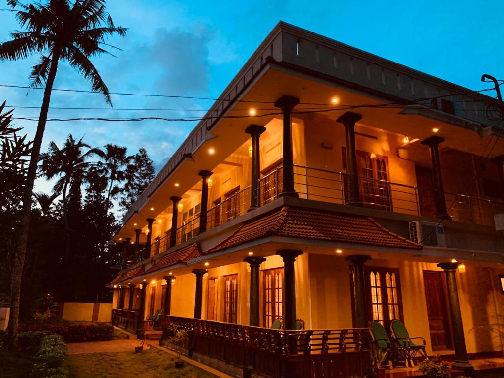 een groot wit gebouw met een balkon en een palmboom bij Surendram Villa in Varkala