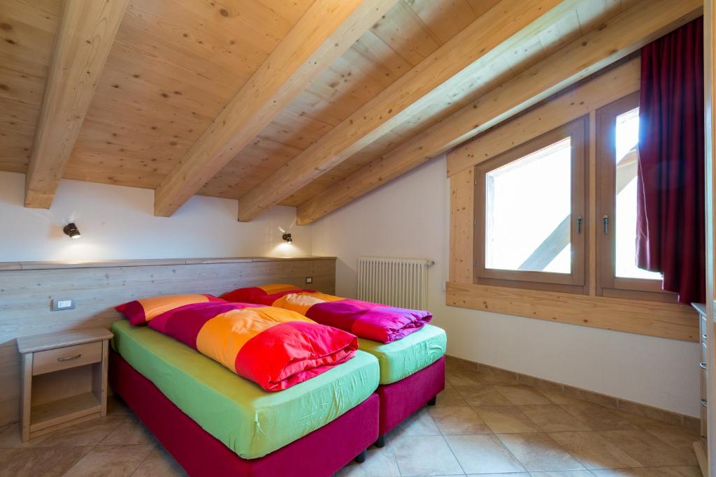 2 letti in una camera con soffitti in legno di Appartamenti Katia a Livigno