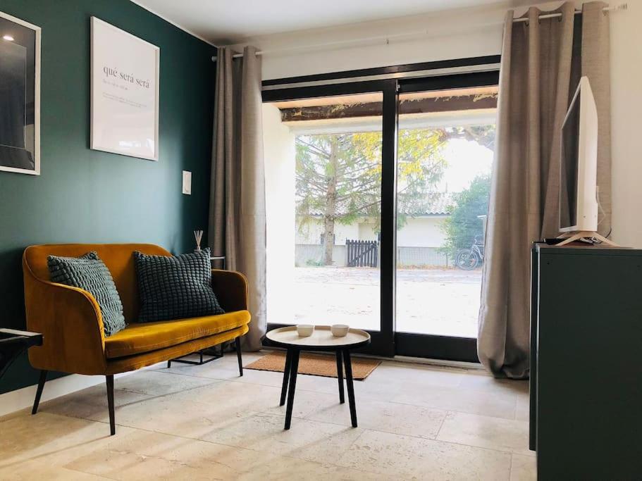 a living room with a couch and a table and a window at Le studio Adhémar - parking sur place in Montboucher-sur-Jabron