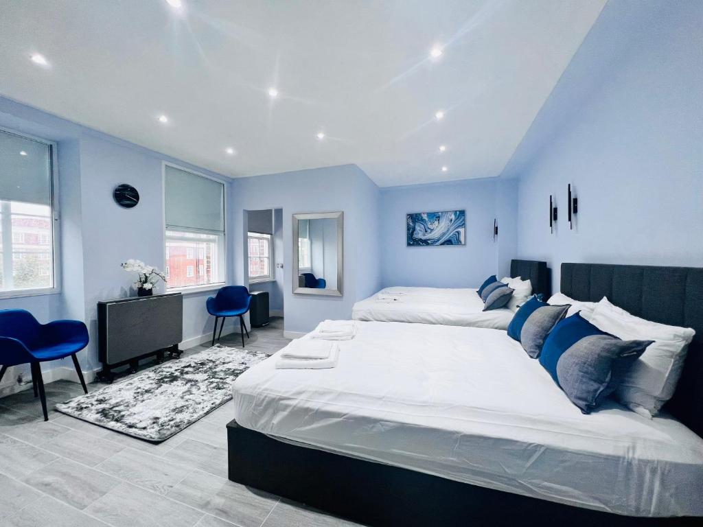 a bedroom with two beds and blue walls at Hyde Park Studio Flats in London