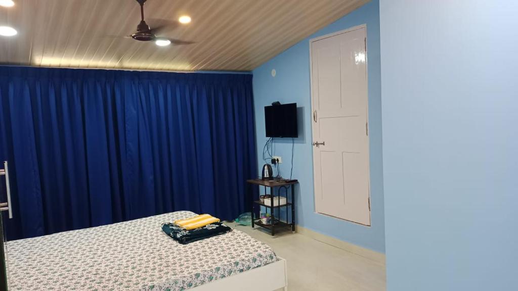 Serene Homestay (Mini -For 2 to 3 Guest) في باناجي: غرفة نوم مع سرير والجدران الزرقاء وتلفزيون
