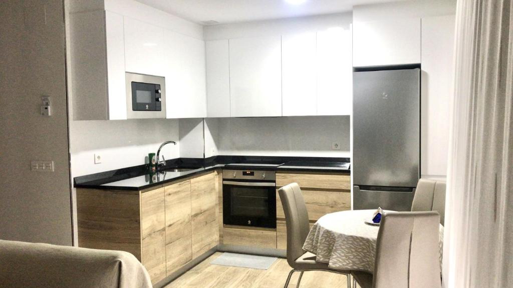 cocina con mesa y nevera de acero inoxidable en Apartamento La Muralla 2D, en Aguilar de Campóo