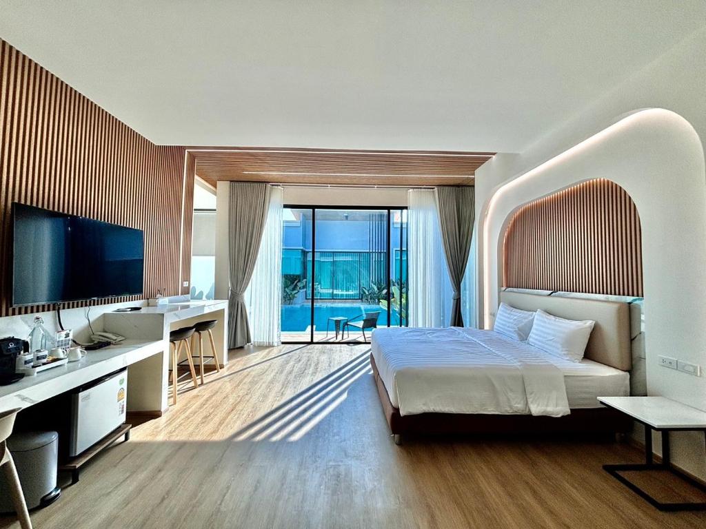 een slaapkamer met een bed, een bureau en een televisie bij Rock Resort Ratchaburi in Ratchaburi