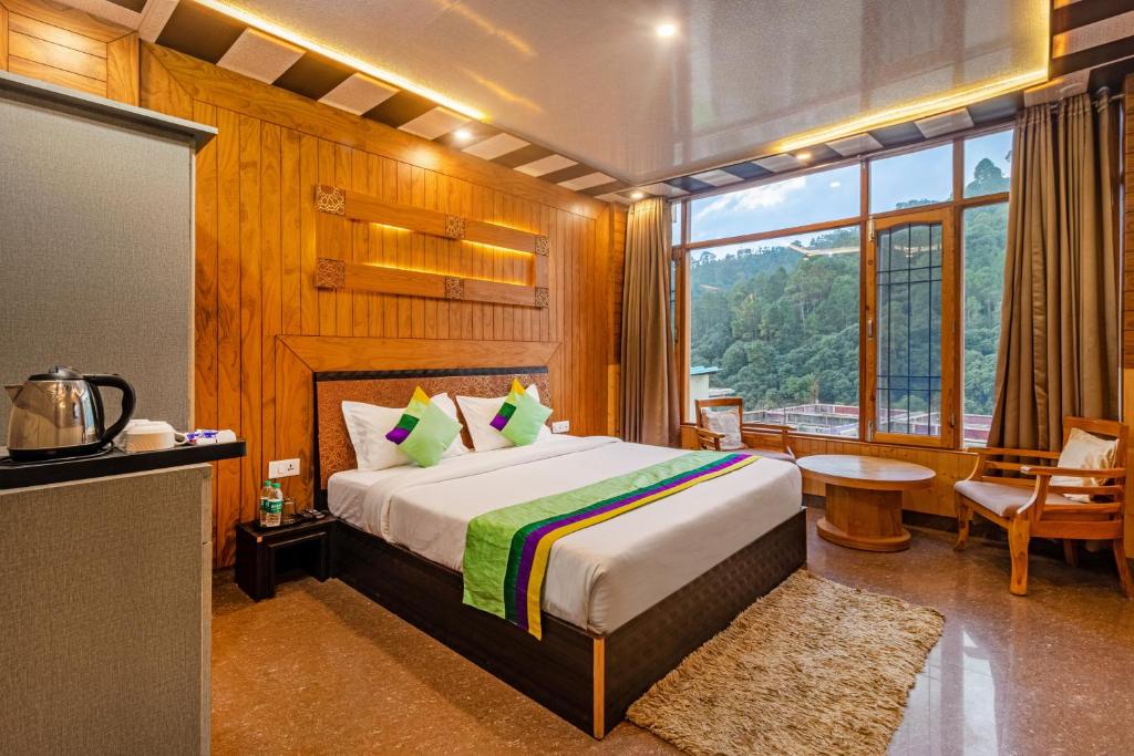 a bedroom with a bed and a large window at Treebo Trend Srishti Vaikunth With Mountain View in Shimla