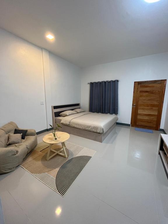Zimmer mit einem Bett, einem Sofa und einem Tisch in der Unterkunft พรสินี 