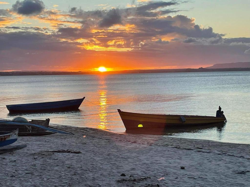 deux bateaux sur la rive d'une plage au coucher du soleil dans l'établissement Ramena Beach Hotel, à Ramena