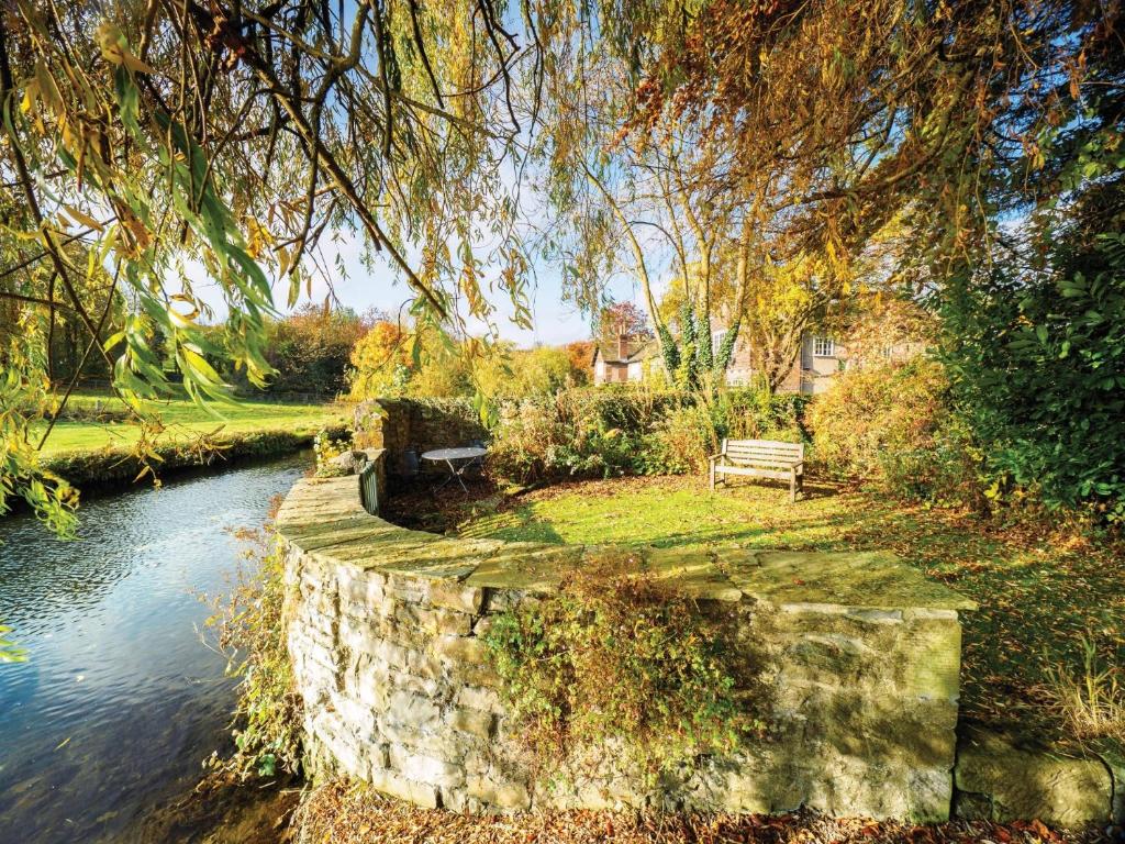 a stone wall next to a river with a bench at 1 Bed in Ashford in the Water PK547 in Ashford