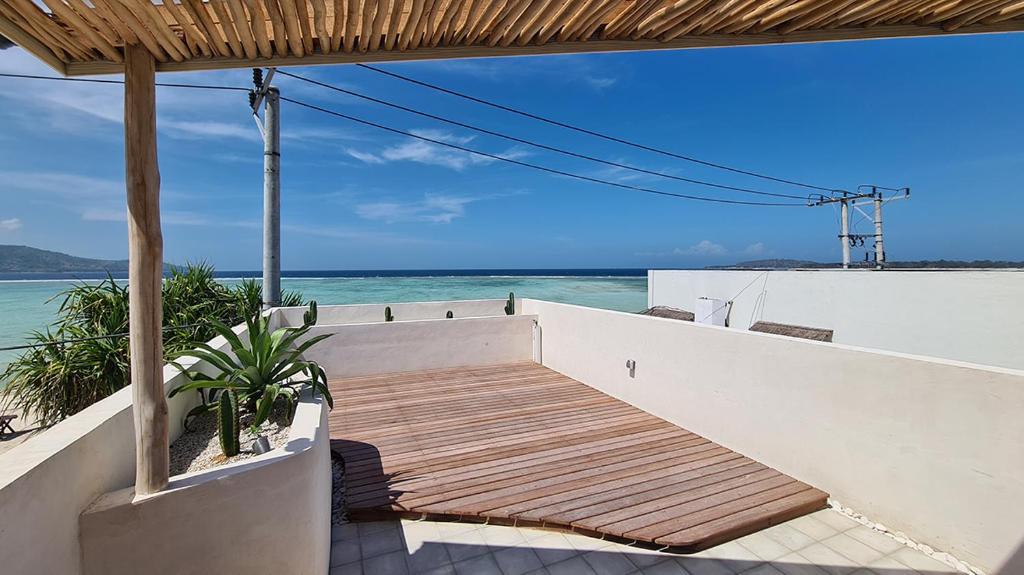 a wooden staircase leading to the beach with the ocean at Shore Thing Gili Air Beachfront Apartment in Gili Air