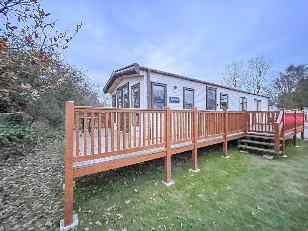 a mobile home with a deck and a fence at Beautiful 6 Berth Caravan At Caldecott Hall Country Park, Norfolk Ref 91150c in Great Yarmouth