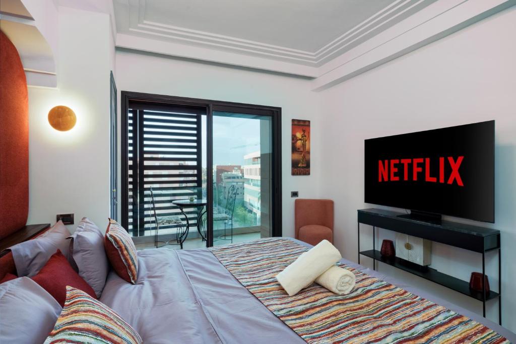 Schlafzimmer mit einem Bett, einem TV und einem Balkon in der Unterkunft Hyper Centre - Gueliz - Plaza - Zara - Vue Dégagée " Récemment rénové " in Marrakesch