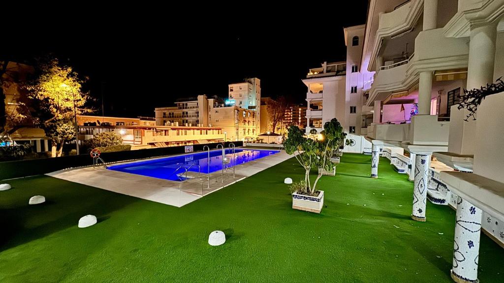 - une piscine avec de l'herbe verte à côté d'un bâtiment dans l'établissement Carihuela Playa Los Nidos 1, à Torremolinos