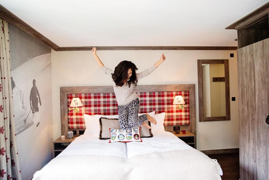 a woman jumping on top of a bed at Hotel Bristol Verbier in Verbier