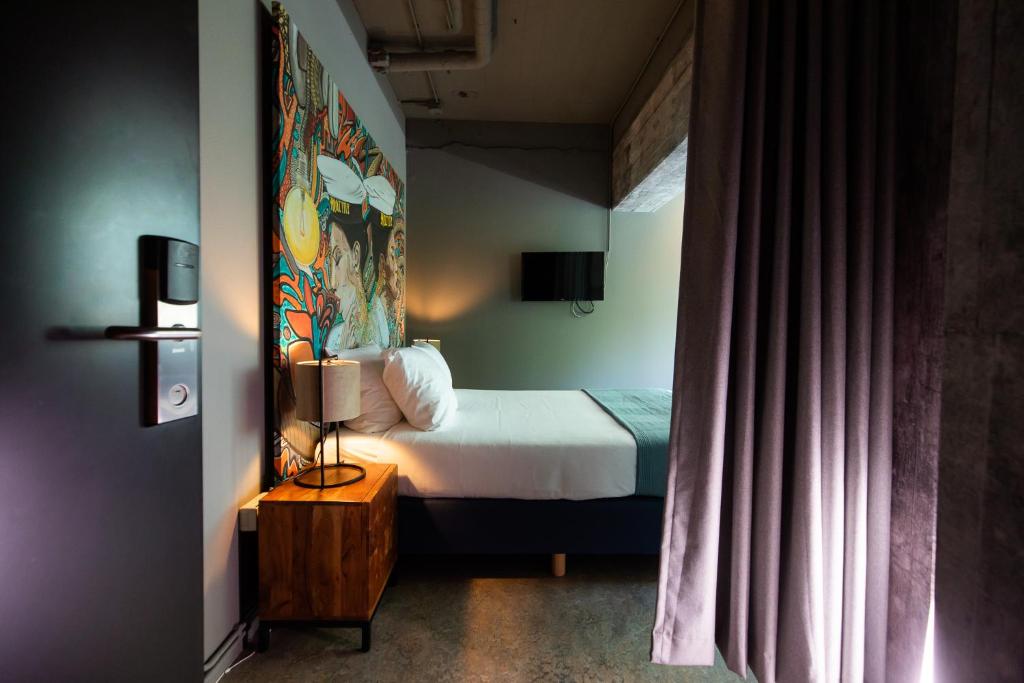 阿姆斯特丹的住宿－Rooms25，卧室配有一张床,墙上挂有绘画作品