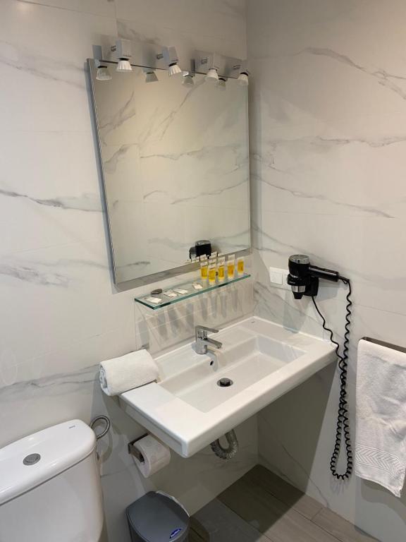 a white bathroom with a sink and a mirror at Apartamentos HC Burriana Playa in Nerja