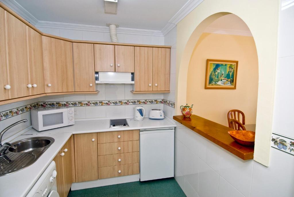 a kitchen with a sink and a microwave at Apartamentos HC Burriana Playa in Nerja