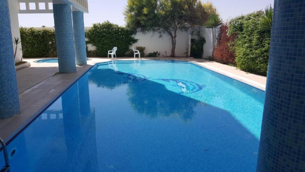 uma grande piscina azul com duas cadeiras em Appartement Vue Sur Mer Turquoise em Mahdia