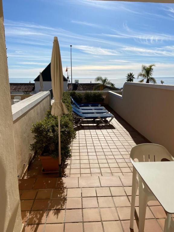 a patio with a table and an umbrella on a balcony at Apartamentos HC Burriana Playa in Nerja