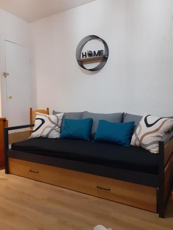 - un canapé avec des oreillers bleus et un miroir mural dans l'établissement Le Sappey-Pied des pistes-Parking gratuit, à Les Deux Alpes