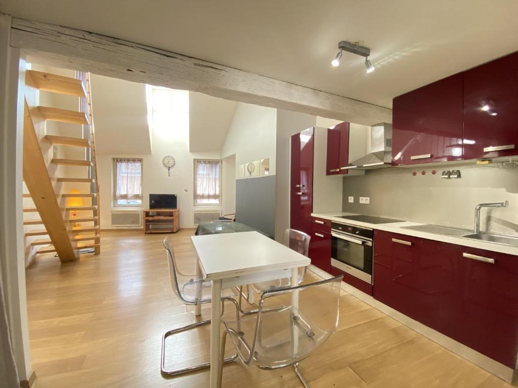 ロデーズにあるLe Duplex Ruthenois, Rodez centreのキッチン(赤いキャビネット、テーブル、椅子付)
