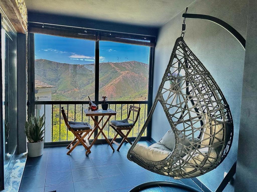 une chambre avec une chaise suspendue et une table avec vue dans l'établissement Love, made in xisto, à Piódão