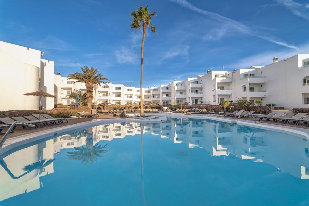 une grande piscine en face d'un hôtel dans l'établissement Hotel Siroco - Adults Only, à Costa Teguise
