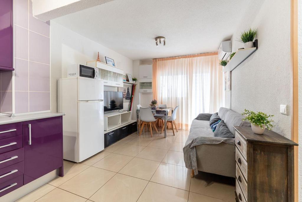 een keuken en een woonkamer met een bank en een koelkast bij Apartamento en el centro a un minuto de la playa in Benidorm