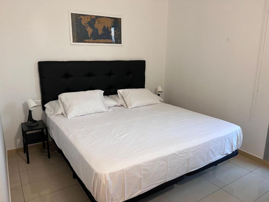 1 cama con sábanas blancas y cabecero negro en una habitación en FIRA Gran Vía 2 - Private Rooms in a Shared Apartment - Habitaciones Privadas en Apartamento Compartido, en Hospitalet de Llobregat