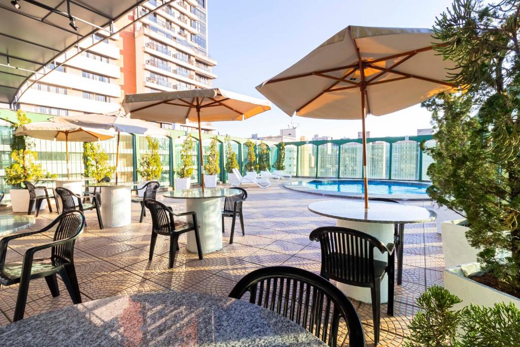 un patio al aire libre con mesas, sillas y sombrillas en Hotel Nacional Inn Curitiba Estação Shopping en Curitiba