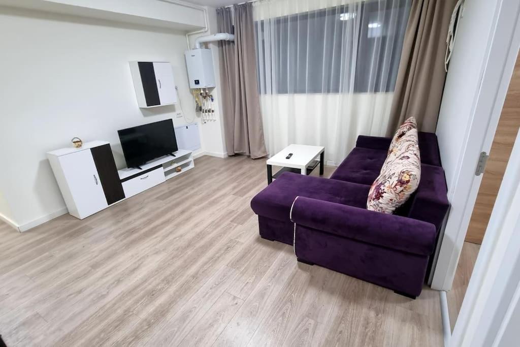 ein Wohnzimmer mit einem lila Sofa und einem TV in der Unterkunft Apartament CWA 3 Aeroport Otopeni in Otopeni