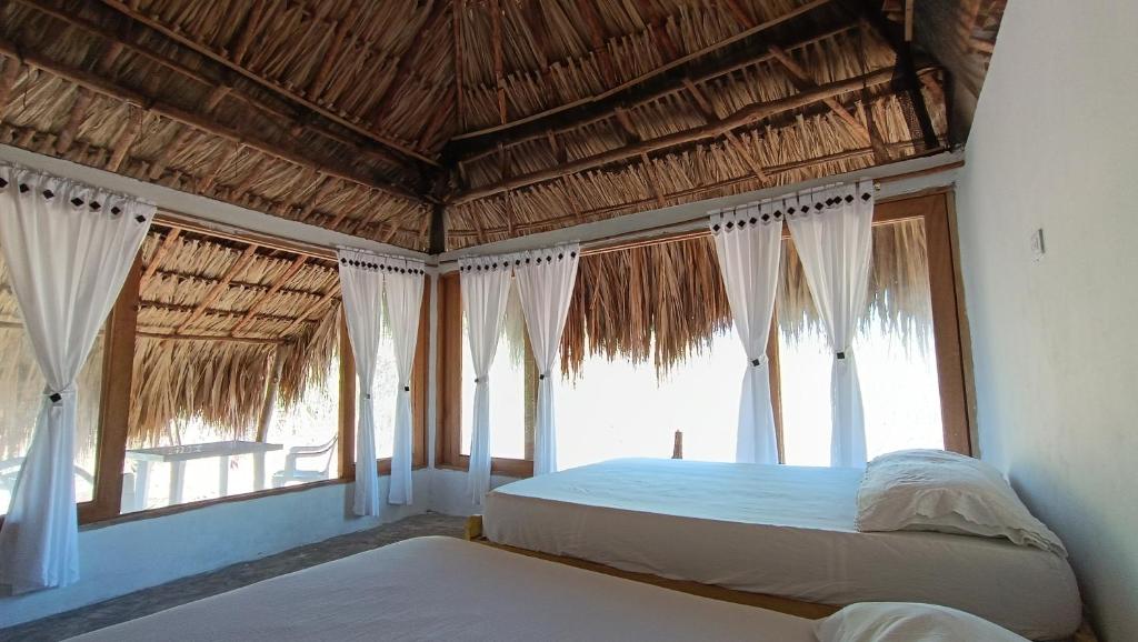 a bedroom with two beds and large windows at El Viejo del Mar in San Bernardo del Viento