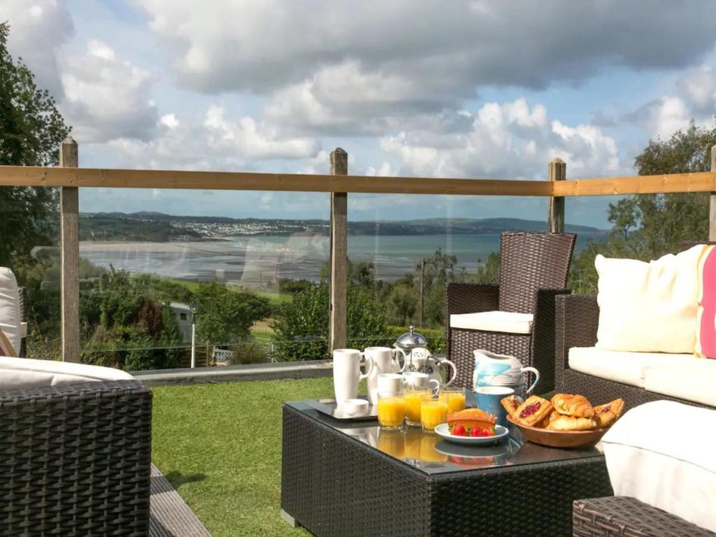 einen Tisch mit einem Frühstückstablett auf einer Terrasse in der Unterkunft Coastal Cottage with Stunning Views Pass the Keys in Llanddona