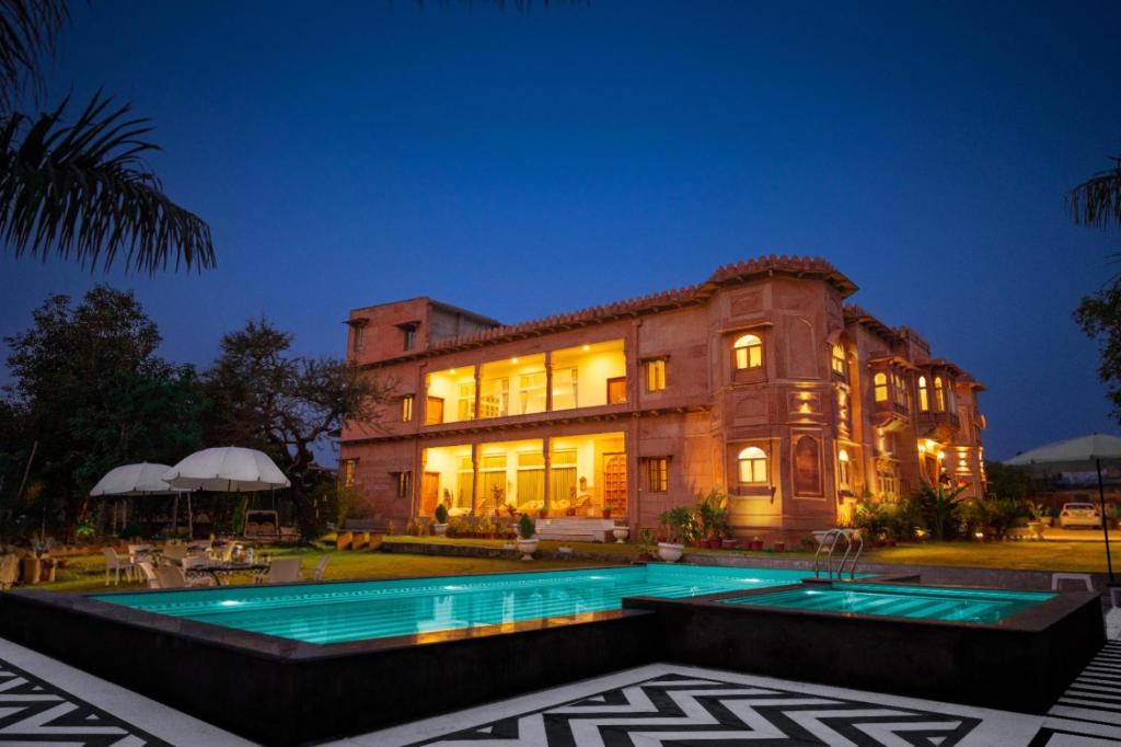 a large building with a swimming pool in front of it at Castle Oodeypore A Boutique stay Udaipur in Udaipur