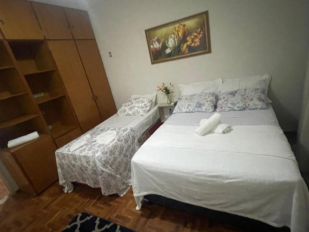 a bedroom with two beds and a cabinet at POUSADA FLOR DO IPÊ in Juazeiro do Norte