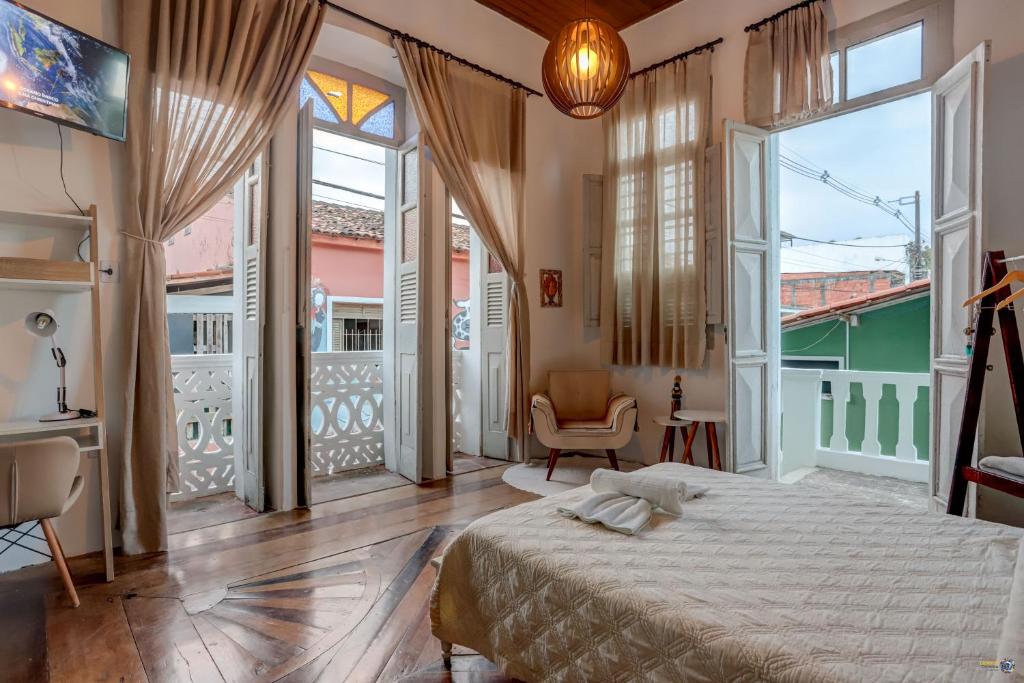 a bedroom with a large bed and large windows at Vila Casarão Verde in Itacaré