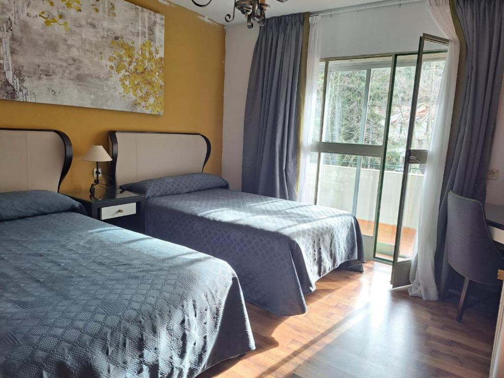 a hotel room with two beds and a window at La Casona del Pinar Albergue in San Rafael