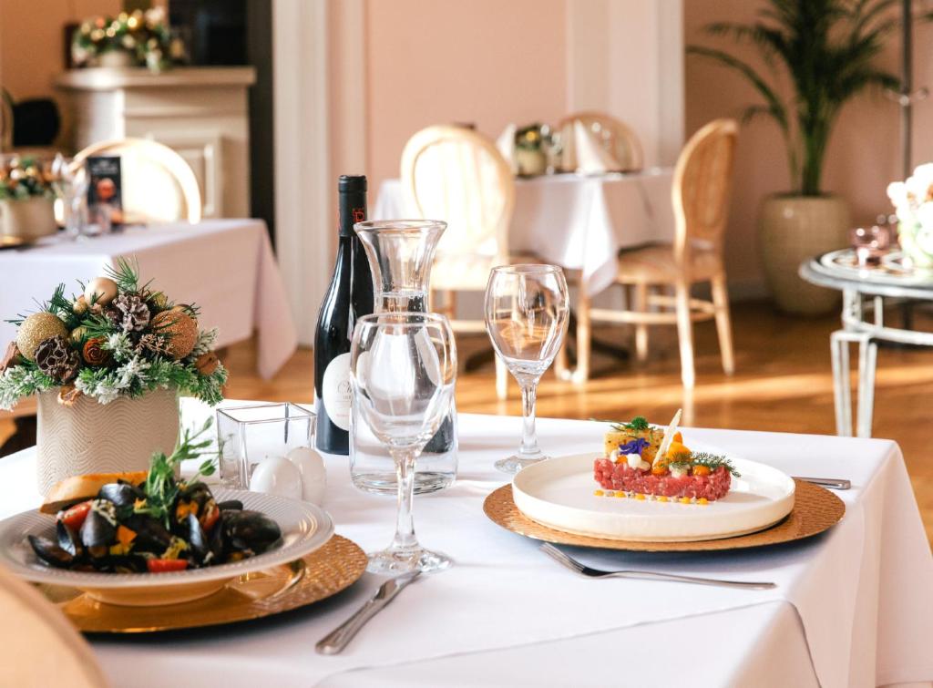 una mesa blanca con platos de comida y copas de vino en Pałac Wojanów, en Wojanów
