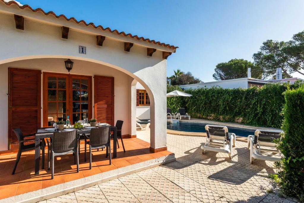 Un patio con mesa y sillas junto a una piscina. en Villa Thea, en Cala Blanca