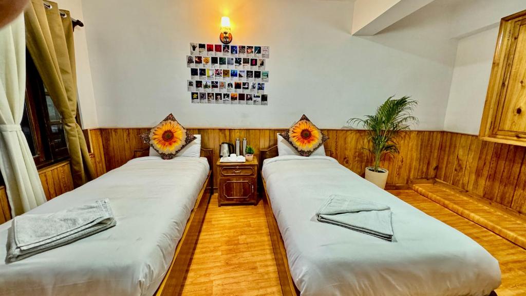 two beds in a room with a table with flowers at Darjeeling Hillside Inn in Darjeeling