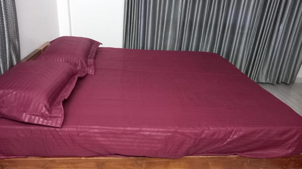 a bed with purple sheets and pillows on it at Niks homestay B in Trichūr