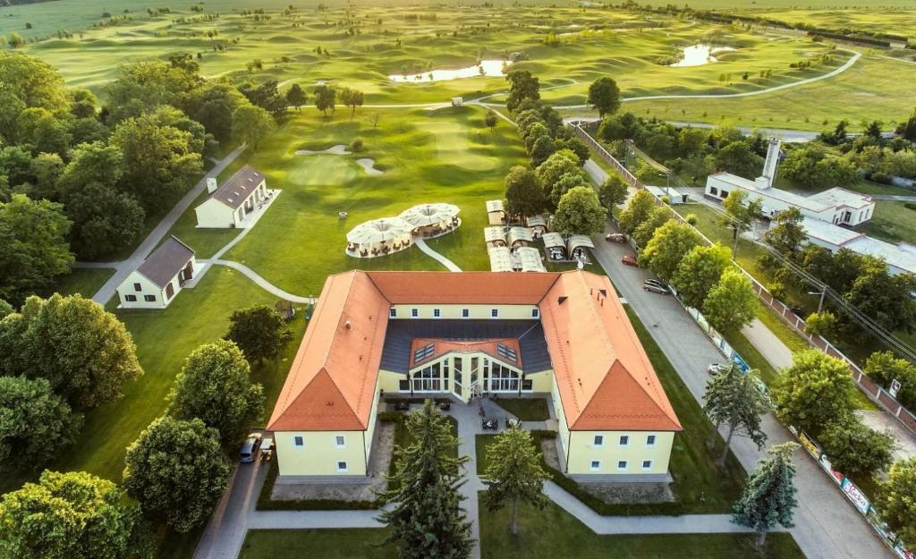 uma vista aérea de uma casa com um campo de golfe em Klaudia's Hotel & Restaurant at Golf Resort, Bač Šamorín em Báč