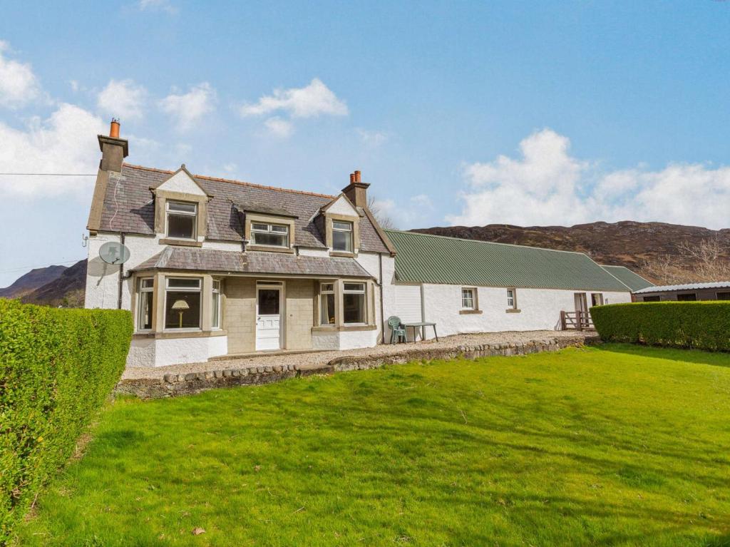 a white house with a green lawn in front of it at 4 Bed in Kinlochewe CA179 in Kinlochewe