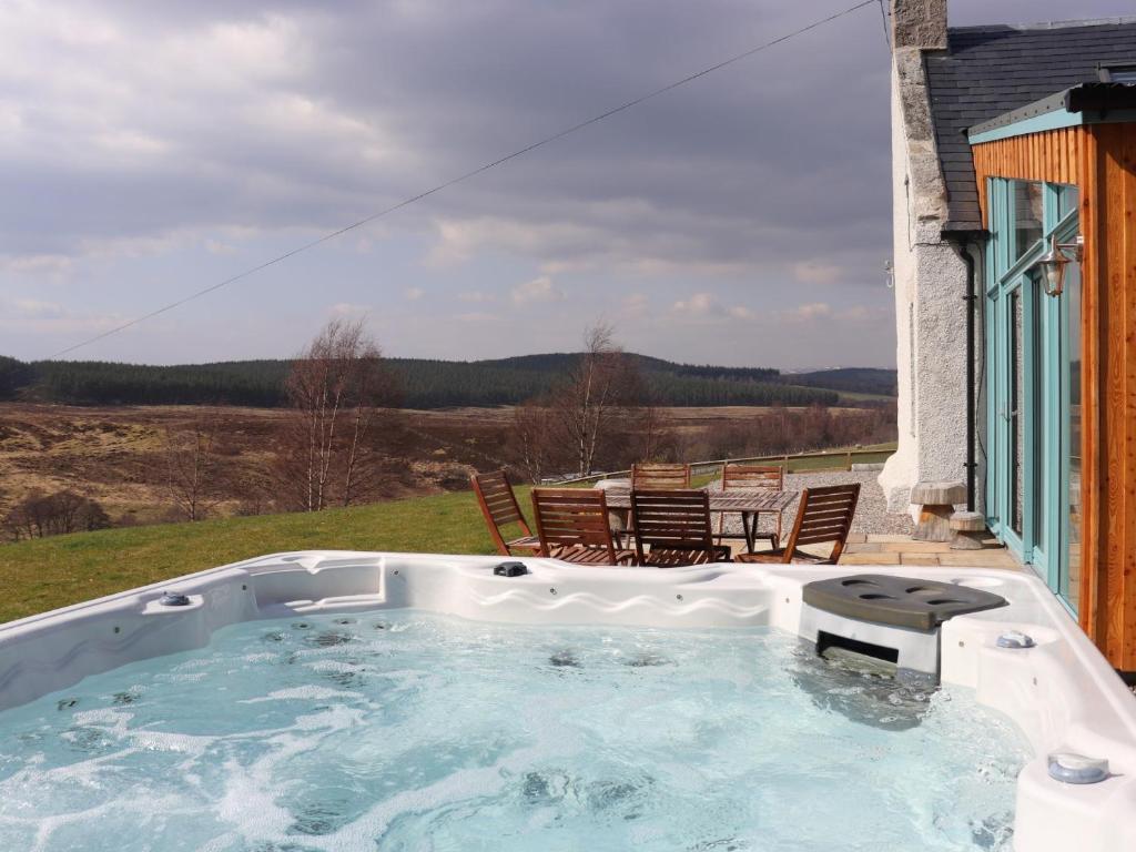 a hot tub on a patio with a table and chairs at 4 Bed in Grantown on Spey CA027 in Grantown on Spey
