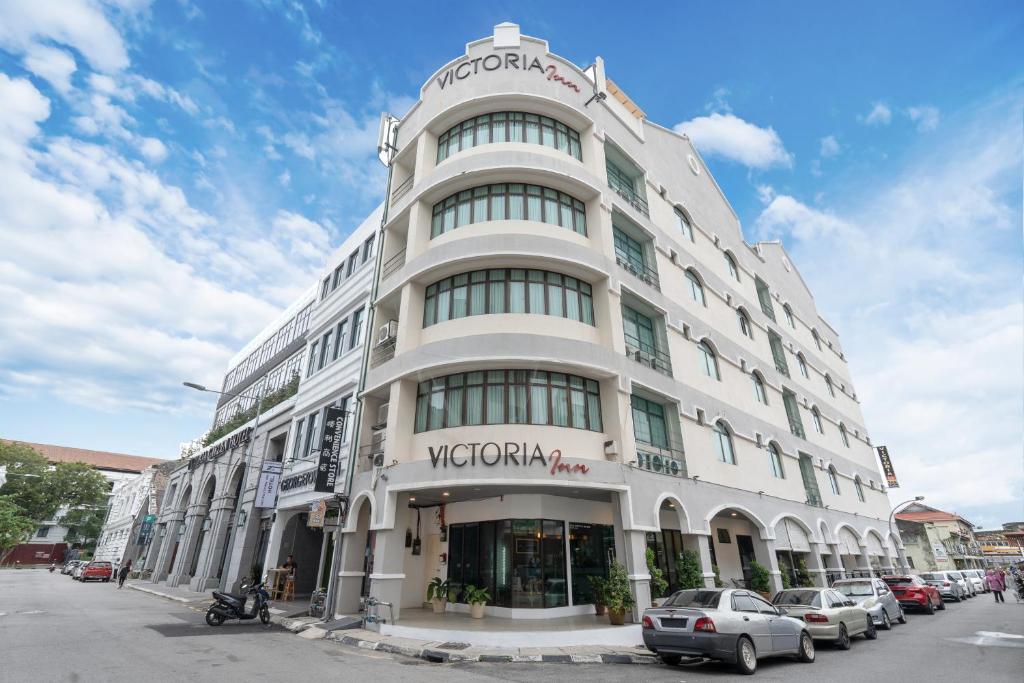 een wit gebouw met auto's ervoor geparkeerd bij Victoria Inn, Penang in George Town