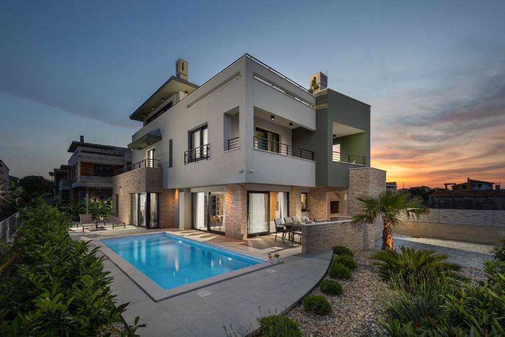 a large house with a swimming pool in front of it at Villa Nadja ZadarVillas in Bibinje